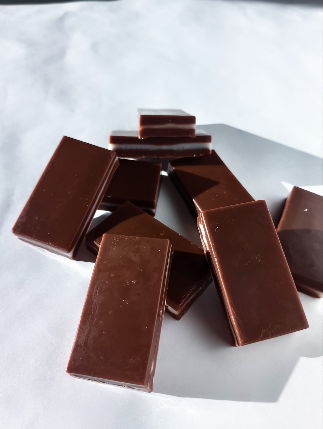 Bombones de jabón de base de jabón con contenido de aceites aromáticos colocados en un montón sobre un fondo blanco.
